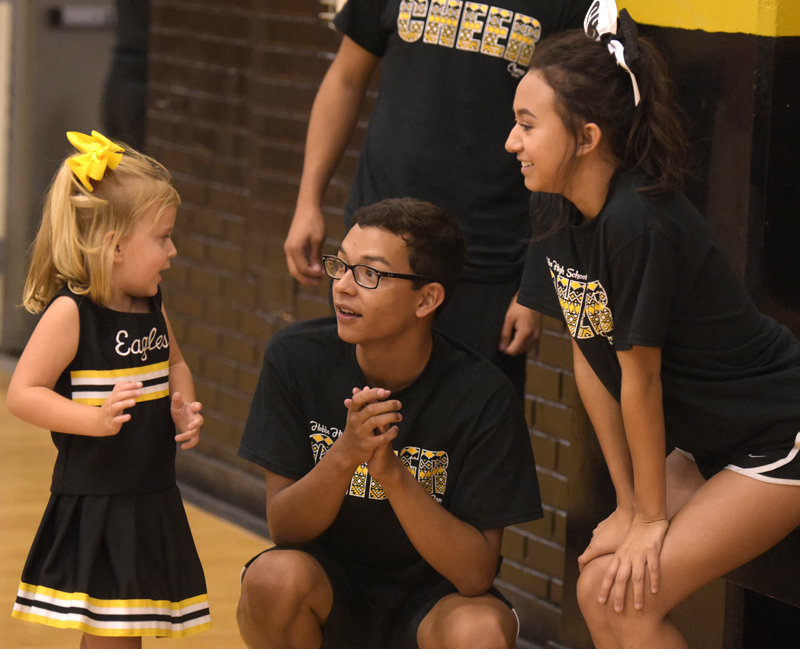 cheerleaders talking to little girl