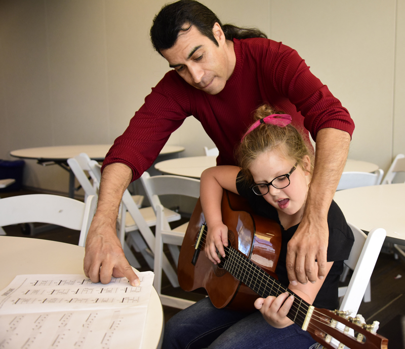 teacher helping student with guitar