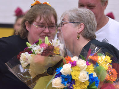mom kissing student holding flowers