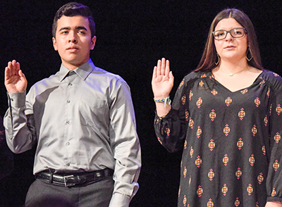 two students with hands in air taking oath