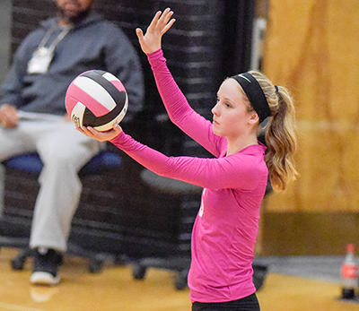girl in pink jersey getting ready to serve ball