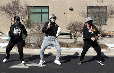 three principals in masks dancing outside