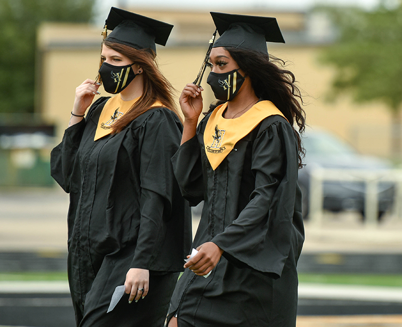 two girls walking in graduation cap and gown