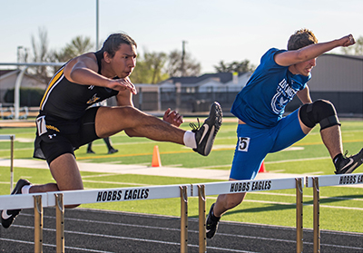 two boys going over hurdles