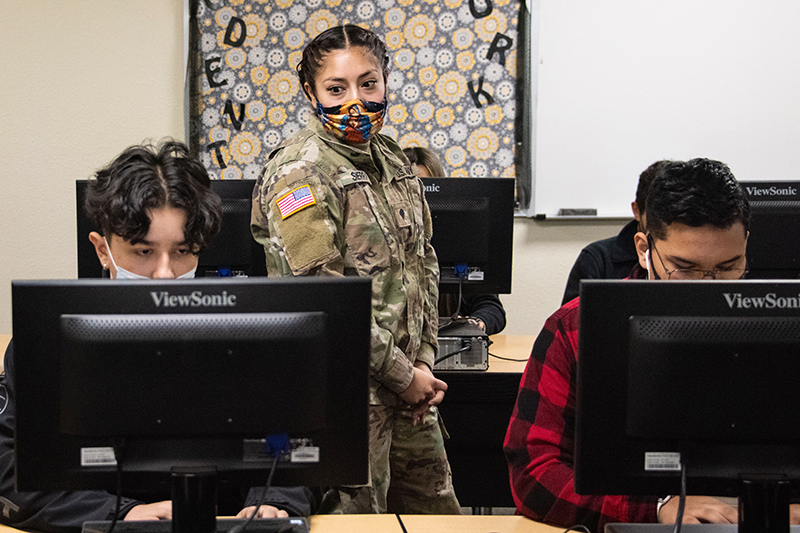 woman in guard uniform looking at students on computers
