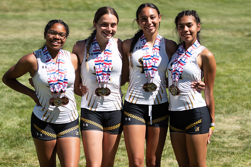four smiling girls wearing medals
