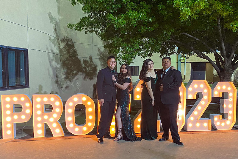 prom students standing in front of lighted sign