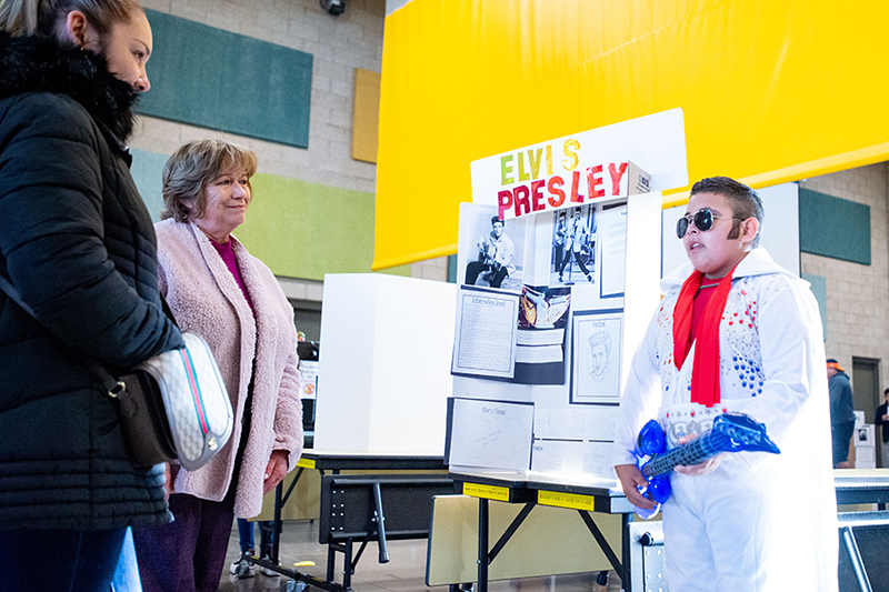 adults listening to student dressed as elvis presley