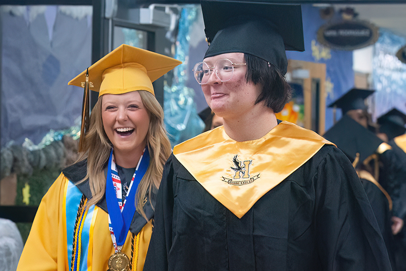 two smiling students in cap and gown
