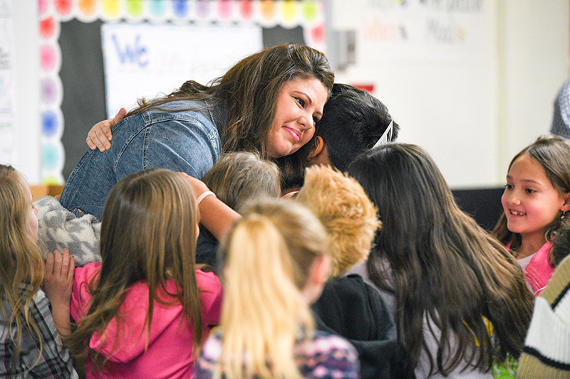 students hugging teacher